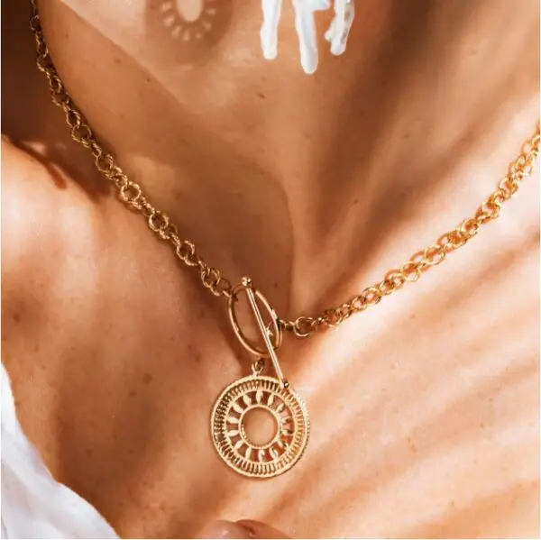 A woman wearing a necklace with a sun symbol on it.