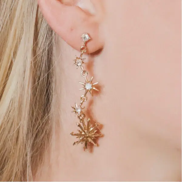 A woman wearing a pair of earrings with stars.