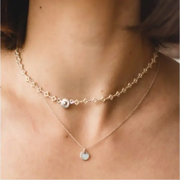 A woman wearing two necklaces on her neck.