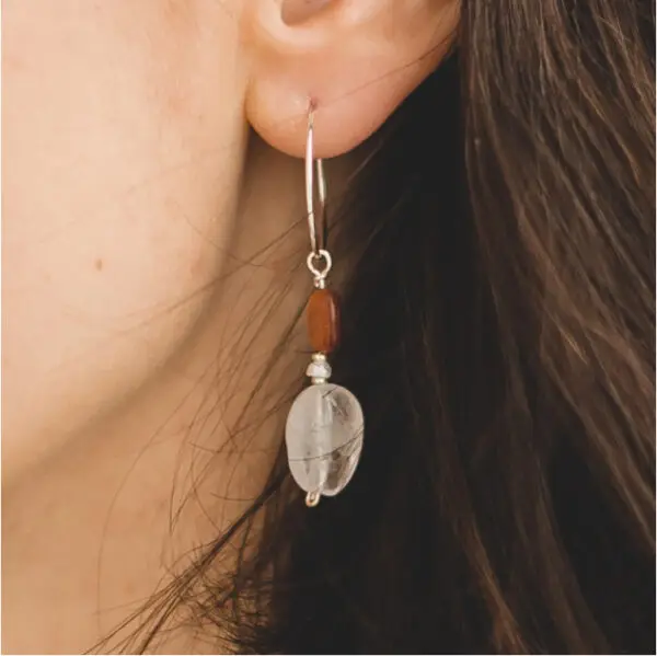 A woman wearing earrings with red beads.