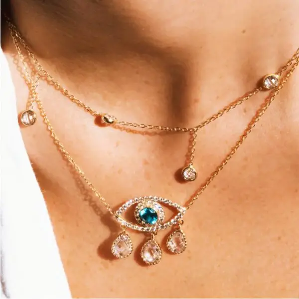 A woman wearing a necklace with an eye and hand design.