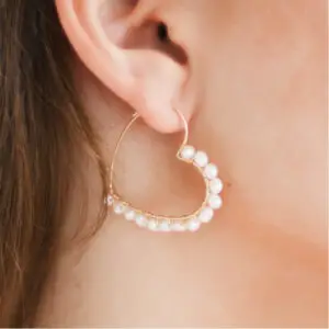 A woman wearing pearl earrings with gold wires.