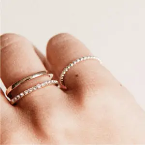 A person 's hand with three rings on it