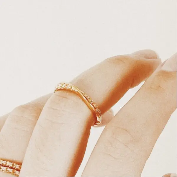 A woman 's hand with two rings on it