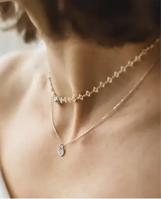 A woman wearing two necklaces with one of them being the same size.