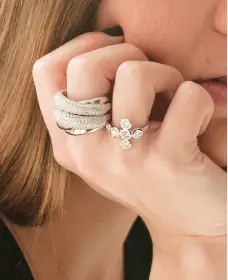 A woman wearing multiple rings with one flower on her finger.