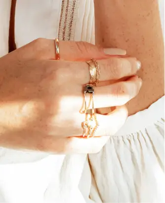 A woman wearing multiple rings and holding onto chains.