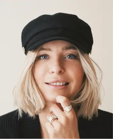 A woman with short blonde hair wearing a black hat.