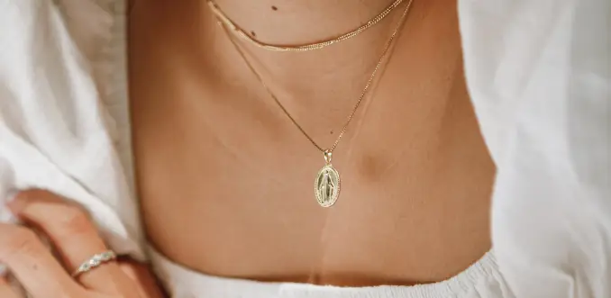 A woman wearing a necklace with a cross on it.