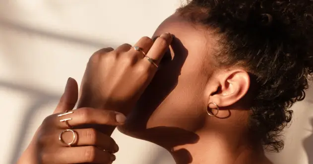 A woman with her hand over her eye.